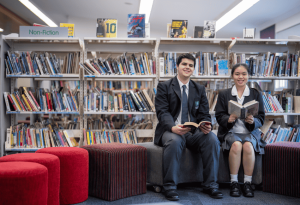 A photo showing two students sitting together in their school library reading books